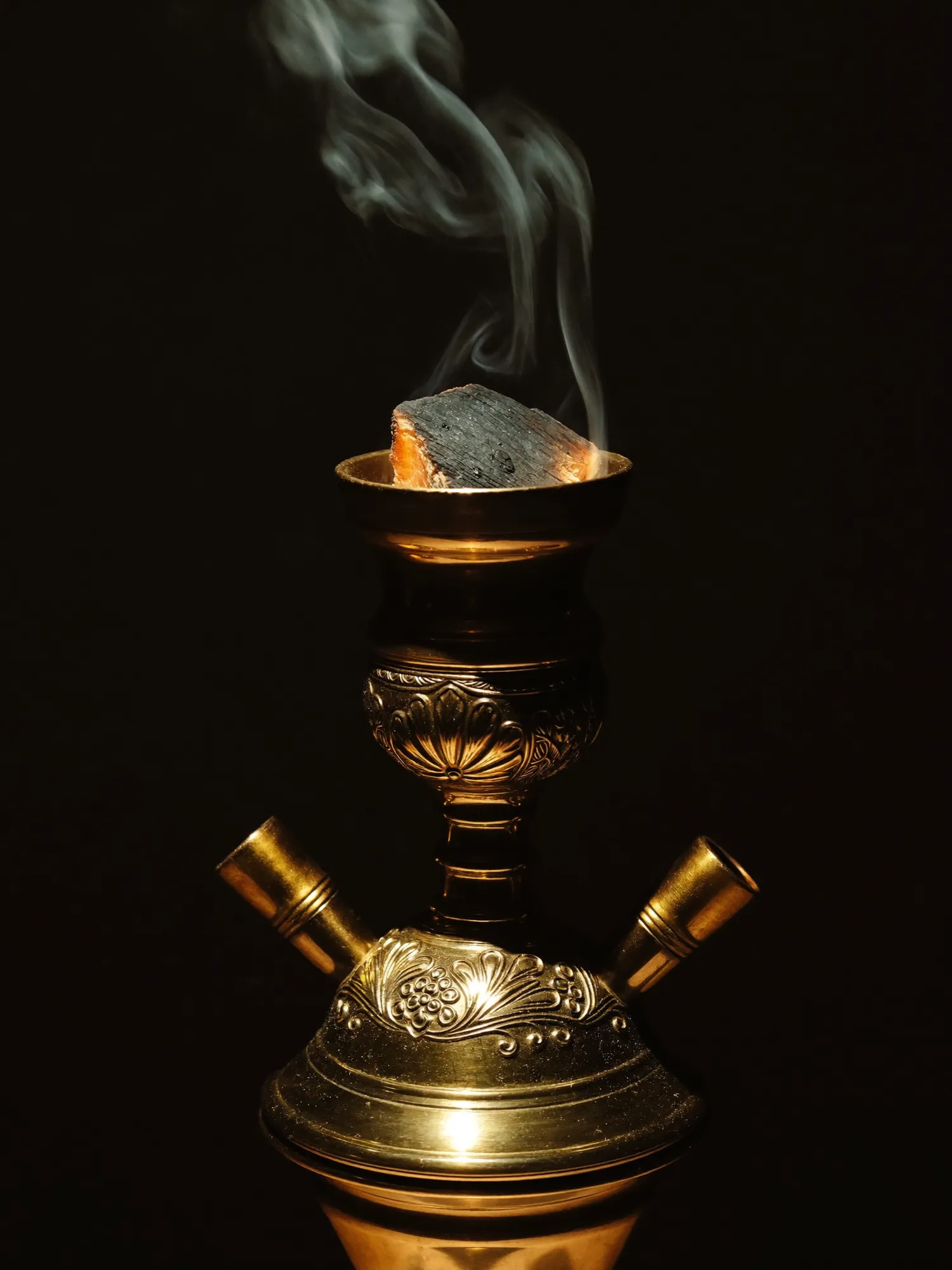 A brass hookah bowl with glowing coals
